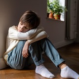 Ein Junge sitzt traurig im Wohnzimmer alleine