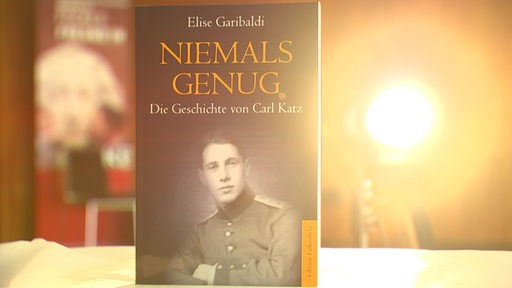 Das Buch mit dem Titel Niemals Genug von der Autorin Elise Garibaldo steht auf einem Tisch. 
