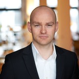Ein Mann blickt mit ernstem Gesichtsausdruck in die Kamera 