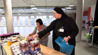 Eine Nonne verteilt Lebensmittel.