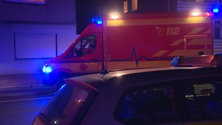 Ein Krankenwagen fährt mit Blaulicht an einem Polizeiauto vorbei.