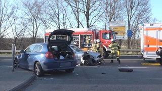 Zwei zerstörte Autos nach einem Unfall auf einer Landstraße.