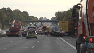Blick auf den Unfall auf der A1: Polizeiwagen, demolierter Lkw