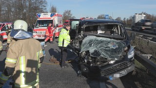 Unfallwagen mit zerstörter Front, Einsatzkräften stehen um den Wagen herum