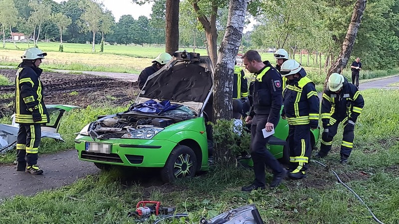 Ein Auto lehnt nach einem Unfall gegen einen Baum.