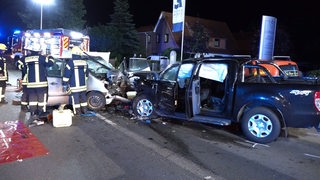 Zwei Autos, die nach einem frontalem Zusammenstoß nachts auf der Straße stehen.