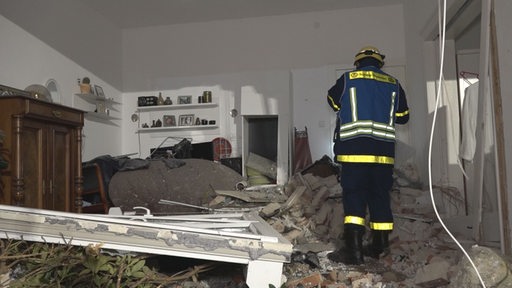 Feuerwehrmann begutachtet Unfallstelle in Oldenburger Wohnhaus, überall liegen Trümmer