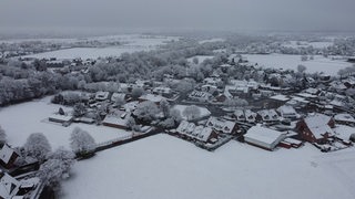 Schnee liegt auf Feldern und Häusern.