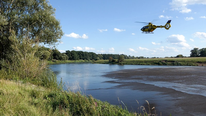 Ein ADAC-Hubschrauber fliegt über einem Fluss