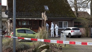 Spurensucher der Polizei im Schutzanzügen vor einem Haus