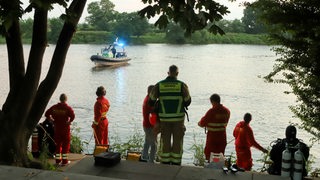 Rettungskräfte schauen auf eine Rettungsboot in der Weser