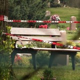 Polizei-Absperrband hängt vor einer Bank auf einem Friedhof.