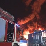 Ein Feuerwehrauto vor dem brennenden Gelände eines Recyclinghofs in Hatten.