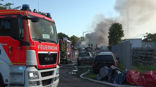 Feuerwehr-Autos vor dem Gelände in Hatten, das gebrannt hat.