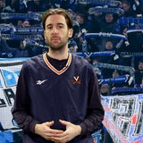 Ein Mann steht vor einem Hintergrund, auf dem HSV-Fans zu sehen sind