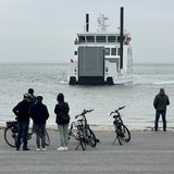 Passanten beobachten in Norderney, wie ein Schiff anlegt. 
