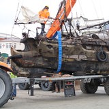 Ein kaputtes Schiff auf einem Lastwagen.