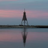 Ein Seezeichen spiegelt sich bei Sonnenuntergang im Wasser.