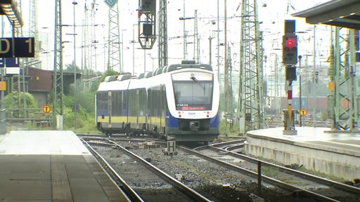 Ein Zug der Nord-West Bahn fährt aus dem Bremer Hauptbahnhof ab. Zu sehen sind außerdem die Gleisanlagen und zwei Bahnsteige.