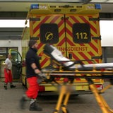 Ein Rettungssanitäter fährt eine Trage vor einen Rettungswagen.