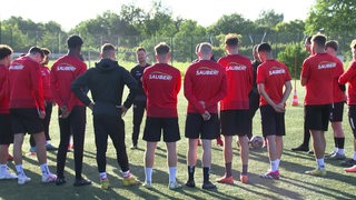 Die Spieler des FC Oberneuland bilden während einer Trainingseinheit einen Kreis um ihren Trainer.