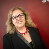 Özlem Ünsal (SPD), Kandidatin für das Amt der Senatorin für Bau, Verkehr und Stadtentwicklung, steht vor einer roten Wand. 