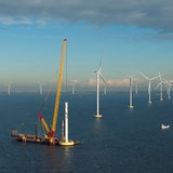 Ein Kran baut eine Offshore-Windkraftanlage zusammen.