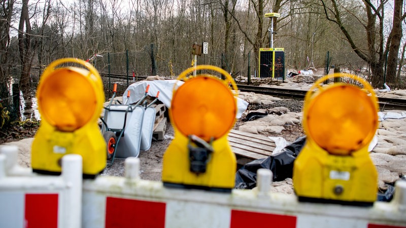 Eine mobile Anlage zur Videoüberwachung steht auf einem durch Sandsäcke gesicherten Deich.