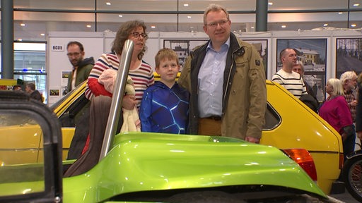 eiane Familie steht zwischen zwei Autos auf der Bremer Classic Motorshow 