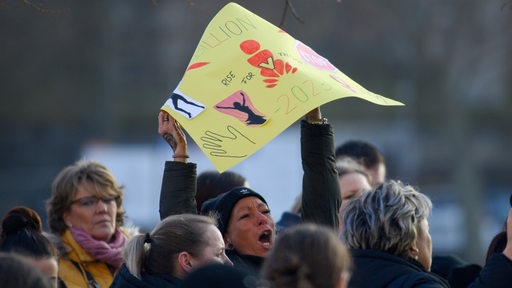 Eine Teilnehmerin eines Tanz-Flashmops hält ein Plakat hoch. 