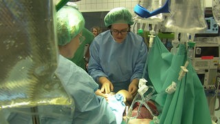 Zwei Ärztinnen stehen während einer simulierten Operation an einem OP-Tisch mit einer Übungspuppe.