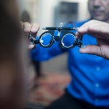 Ein Optiker hält eine Probebrille in der Hand.