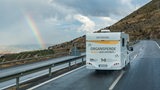 Ein weißer Camper mit der Aufschrift "Organspende Reden wir drüber" fährt auf einer Straße.