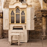 Eine Orgel steht vor einer alten Steinwand in einer Kirche.