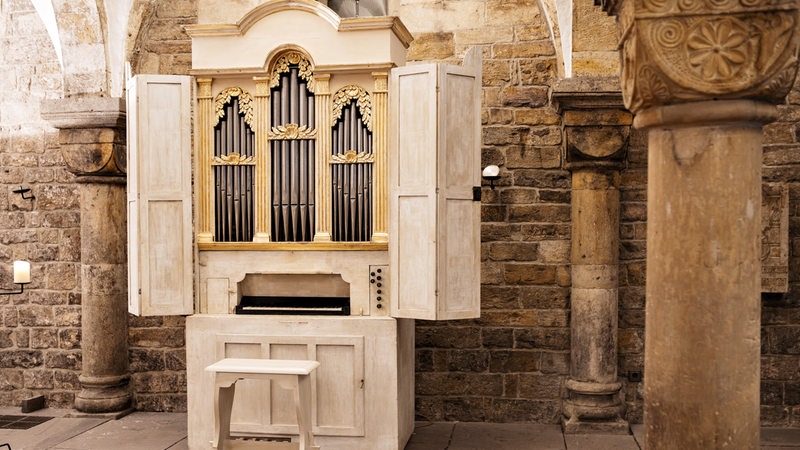 Eine Orgel steht vor einer alten Steinwand in einer Kirche.