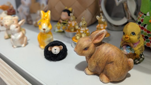 Osterhasen-Figuren stehen auf einem Regalbrett.