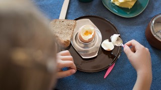 Ein Kind frühstückt ein Hühnerei.