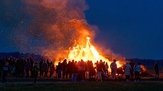 Menschen schauen sich ein Osterfeuer an.