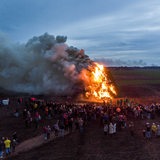 Aus der Ferne ist zu sehen, wie ein Osterfeuer unter großer Rauchentwicklung abbrennt. 