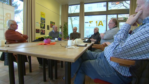 Sechs Männer sitzen um einen Tisch herum in einem Stadtteil-Treff in Osterholz-Tenever.
