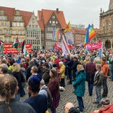Menschen demonstrieren mit Transparenten und Flaggen auf dem Bremer Marktplatz