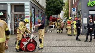 Feuerwehrleute und Polizisten stehen im Bremer Viertel.