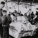 Ein Kind sitzt in einem Panzer auf einem Kinderkarussell auf der Bremer Osterwiese 1968.