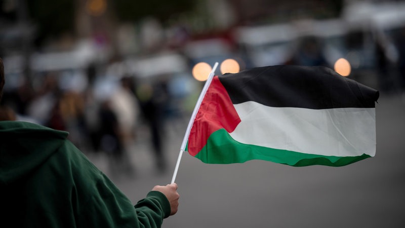 Eine Person hält eine Palästina-Flagge in der Hand