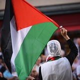 Eine Frau schwenkt einen Palästina-Flagge.