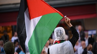 Eine Frau schwenkt einen Palästina-Flagge.