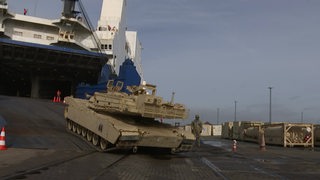 Ein Panzer faehrt mittels einer Rampe von einem Schiff.