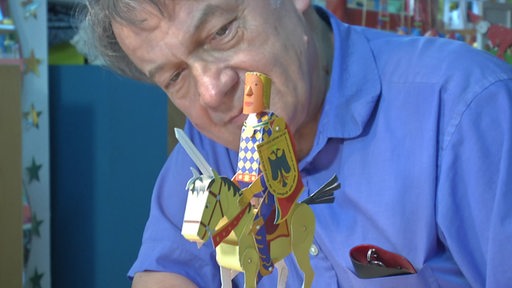 Ein Mann schaut auf ein von ihm angefertigtes Papierfiguren-Kunstwerk.