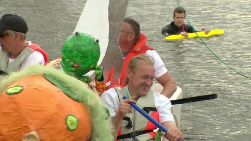 Männer auf einem lustigen selbstgebauten Pappboot bei der Pappbootregatta in Vegesack.