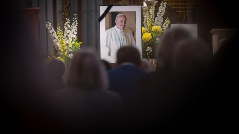 Ein Bild mit Trauerflor von Papst Franziskus steht während eines Gottesdienstes vor dem Altar 